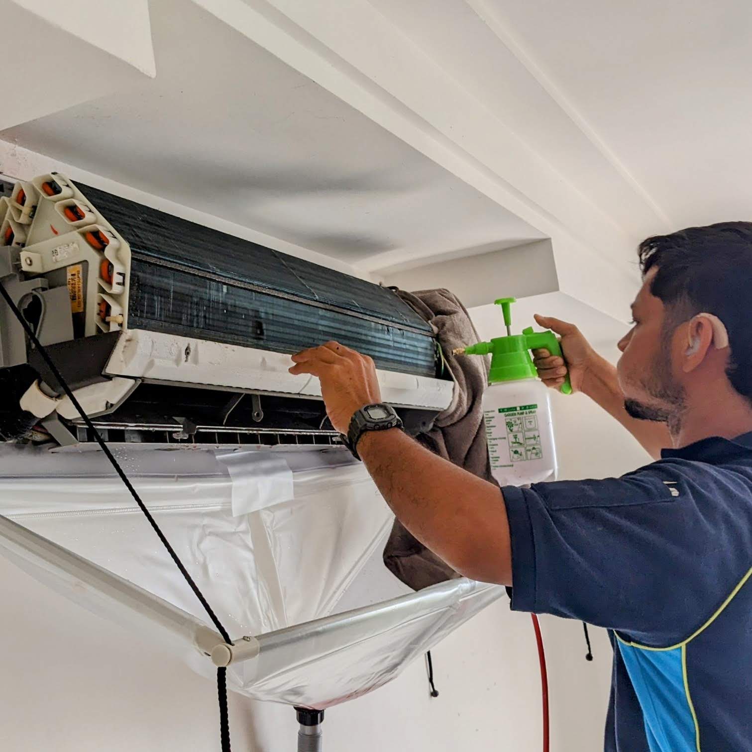 Technician cleaning an indoor aircond unit